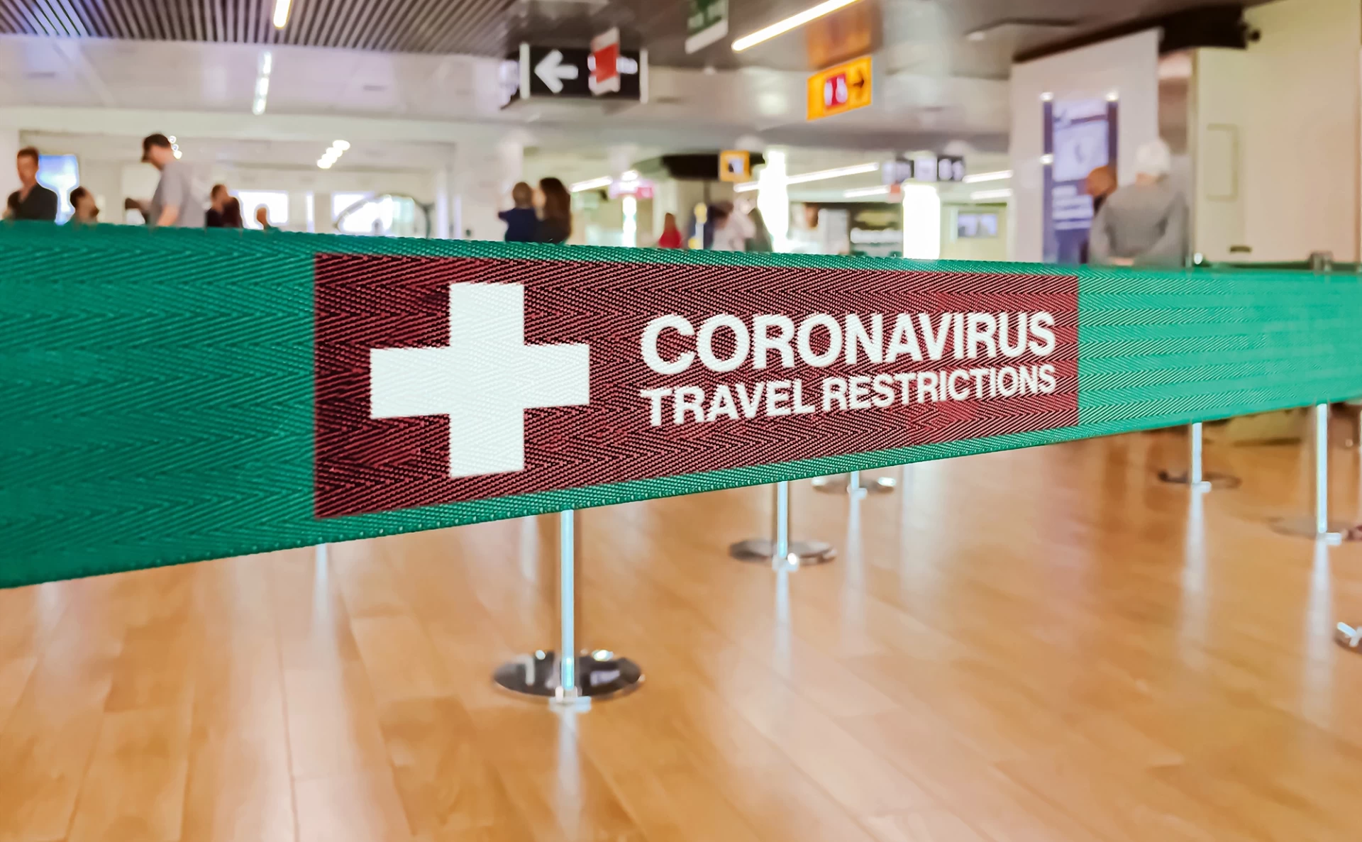 Airport fence barrier with text reading 'Coronavirus travel restrictions'