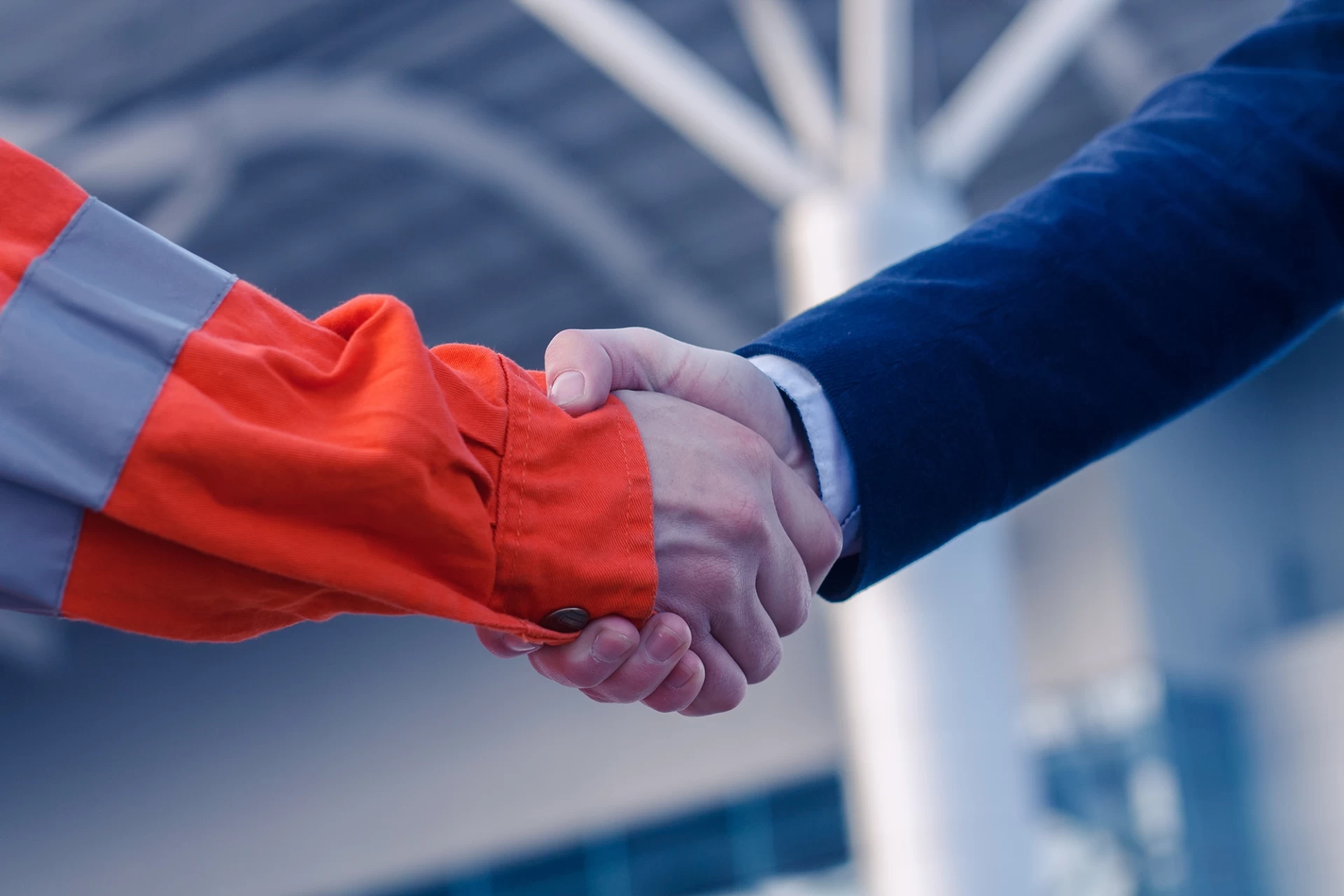 Close-up of a worker and businessman shaking hands.